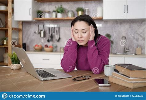 Bored Sleepy Asian Lady Sitting At Desk With Laptop Holding Head