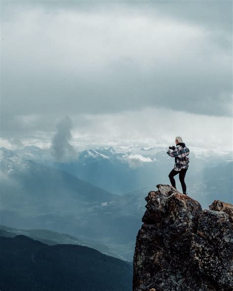 Person Standing On Top Of Rock Mountain During Daytime Photo Free