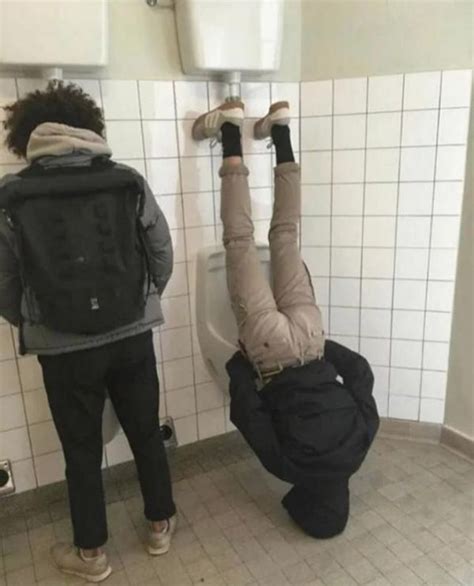 Two People Standing In A Bathroom While One Person Is Upside Down On
