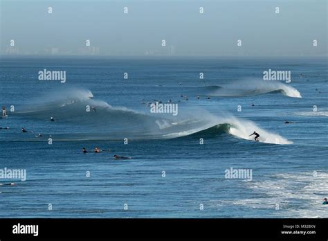 Surfers Surfing Waves With Offshore Wind In Huntington Beach California