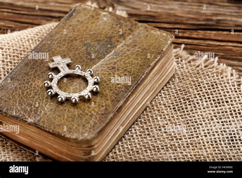 Very Old Prayer Book And Ten Rosary On Wooden Background With Empty