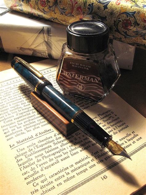 A Fountain Pen Sitting On Top Of An Open Book Next To A Fountain Ink Bottle