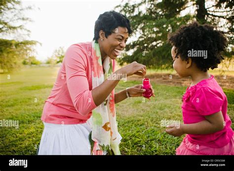 Madre E Hija Negro Soplando Burbujas En El Parque Fotografía De Stock