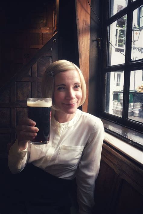 A Woman Sitting At A Table With A Glass Of Beer