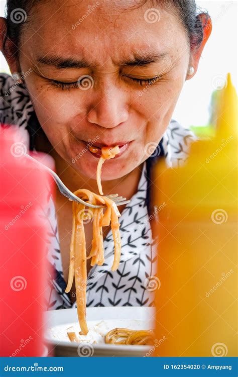 Expression Of An Asian Adult Woman Eating Spicy Pasta In A Restaurant