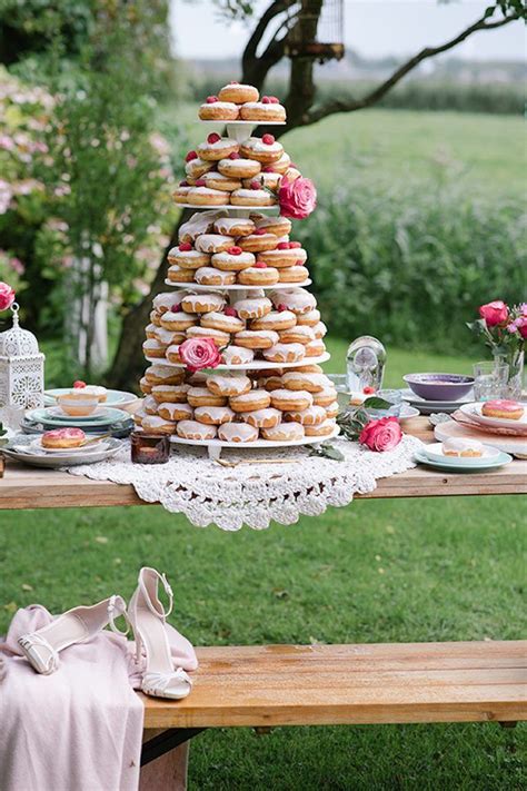 A Table Topped With Lots Of Donuts On Top Of A Wooden Table Covered In Pink Flowers