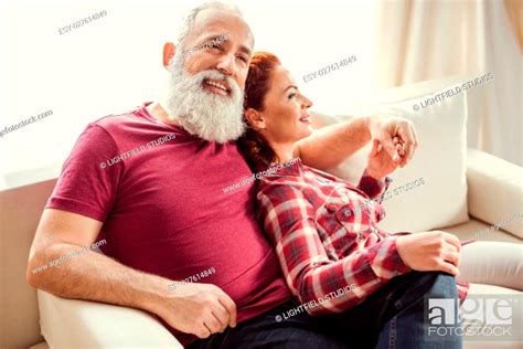 Happy Mature Couple In Love Sitting Embracing On Sofa At Home Stock