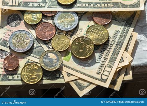 Euro Coins Of Different Denominations On The Background Of Dollar Bills