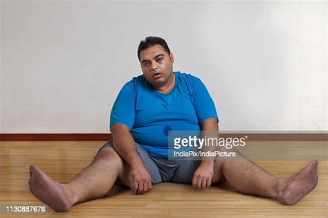 Overweight Man Sitting On The Floor With Legs Spread Apart Tired After