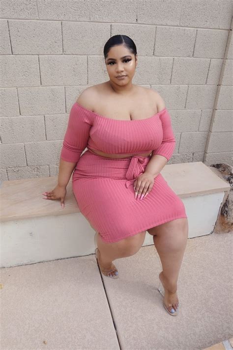 A Woman In A Pink Dress Sitting On A Bench With Her Hands On Her Hips