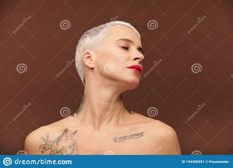 Hembra Serena Con Pelo Rubio Corto Tatuajes En El Cuello Y El Pecho Imagen De Archivo Imagen
