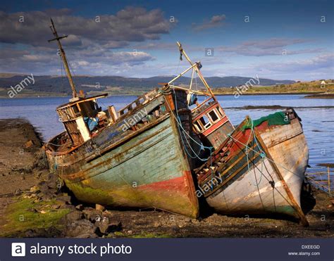 Two Old Boats Sitting On The Shore Near Water