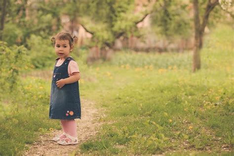 Premium Photo Little Adorable Girl In The Garden Walks On The Path
