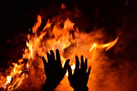 Person Warming Their Hands On The Burning Shiny Fire At Night Stock