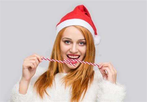 Beautiful Young Woman With Santa Hat Smiling Holding A Candy Cane In