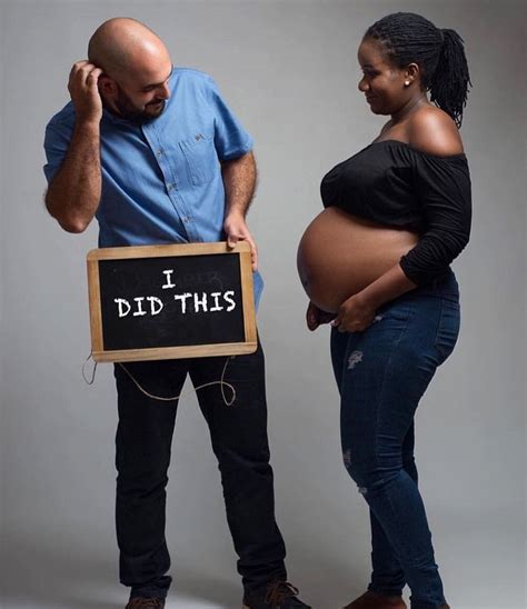 A Pregnant Woman Standing Next To A Man Holding A Sign That Says I Did This