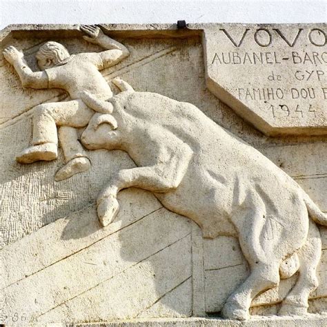 A Statue Of A Man Falling From A Bull On The Side Of A Building With