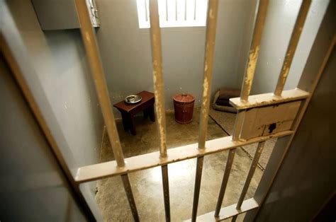 A Jail Cell With Two Small Stools In It