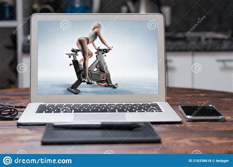 Beautiful Slender And Long Legged Girl Sits On An Exercise Bike Side