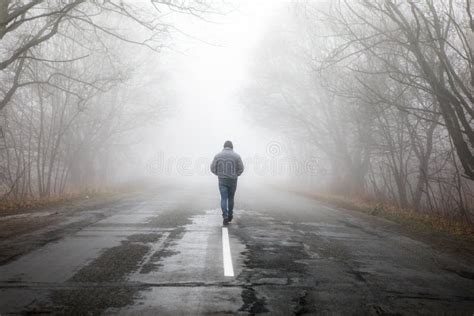 Lonly Man Walk Away Into The Misty Foggy Road In A Dramatic Mystic
