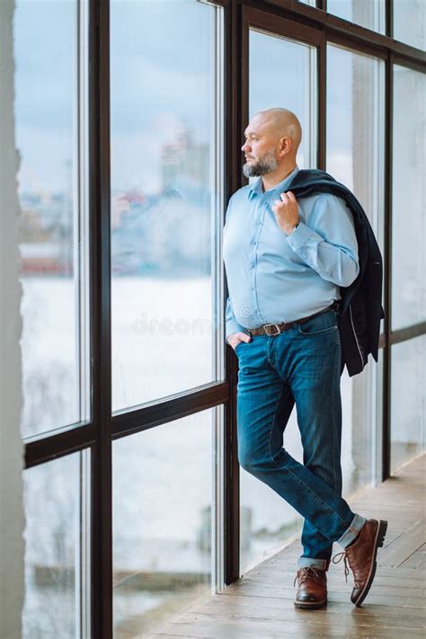 Portrait Of Confident Bald Man With Beard Staying Near Window Looking
