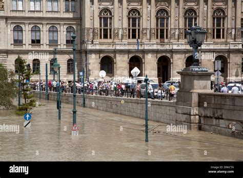 Spectators And Tourists Looking Over At The Flooded Street And Tram On The Burst Banks Of The