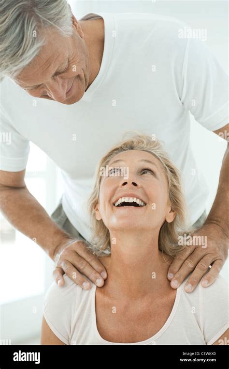 Mature Couple Smiling At Each Other As Man Massages Woman S Shoulders
