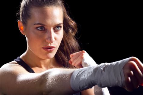 Female Mma Fighter Holding Fist Out Punching On Black Background Stock