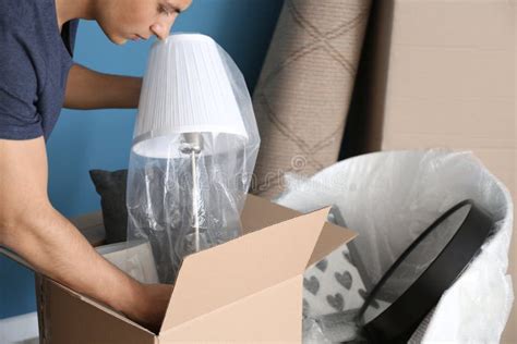 Young Man Unpacking Box Indoors Moving Into New House Stock Photo
