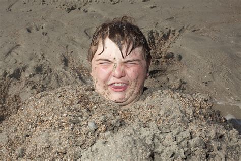 Head Of Young Man Buried In Sand And Making Disgusted Face