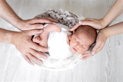 Las Manos De Mamá Y Papá Sostienen Suavemente A Una Niña Recién Nacida