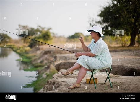 Mature Woman Sitting Fishing By A Lake Stock Photo Alamy