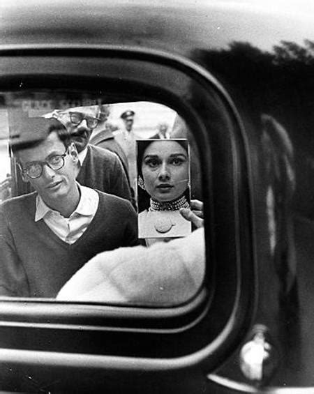 A Man And Woman Are Seen In The Rear View Mirror Of An Old Car As They