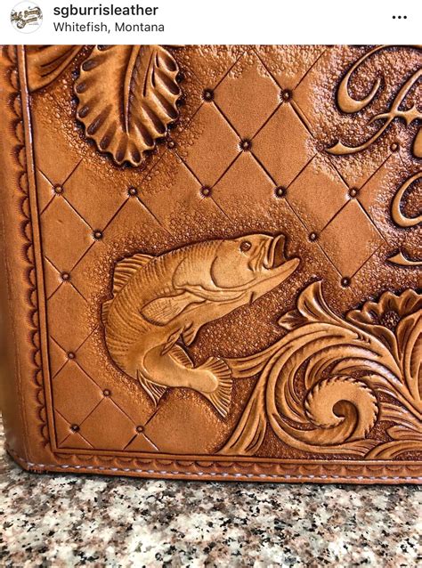 A Brown Wallet With Fish Carved On The Front And Side Sitting On A