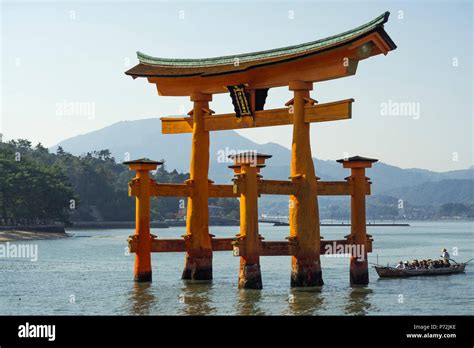 Tourist Passing Through The Floating Red Wooden Torii Gate Of Miyajima