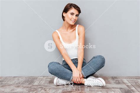 Portrait Of A Casual Happy Woman Sitting On The Floor With Legs Crossed