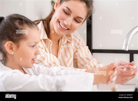 La Hija Pequeña Con Su Madre Lavándose Las Manos En El Baño Fotografía