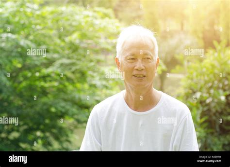 Portrait Of White Hair Asian Senior Adult Man Smiling Standing At Outdoor Park In Morning Stock