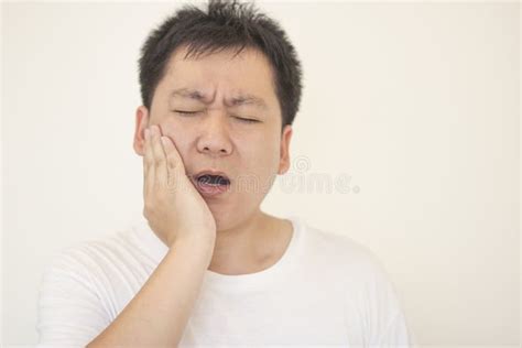 Indoor Shot Of Young Male Feeling Pain Holding His Cheek With Hand