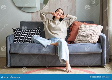 Portrait Of Happy Asian Woman Feeling Lazy Stretching On Sofa And Smiling Pleased Relaxing At