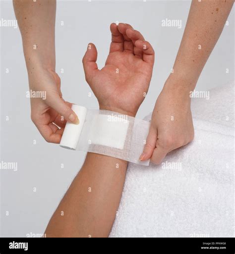 Womans Hands Covering Wound On Boys Wrist With Bandage Close Up