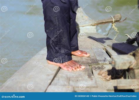 Feet Of Poor Barefoot Fisherman In Blue Pants In Old Wooden Canoe In