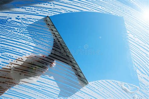 cleaning window with sponge and detergent female hand rubbing soapy glass against blue sky