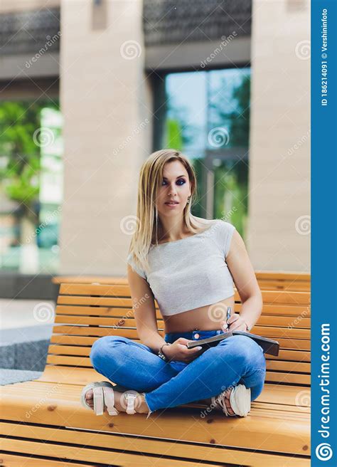Girl Writes In A Notebook Sitting On A Bench In The Park Stock Image
