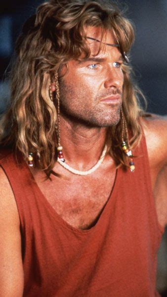 A Man With Long Hair Wearing A Red Tank Top And Gold Earring Necklaces