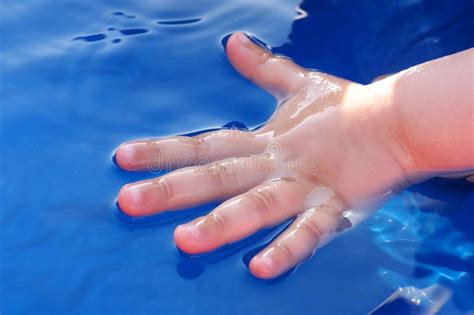 Child Hand Half Dipped In Water Of Blue Plastic Swimming Pool Stock