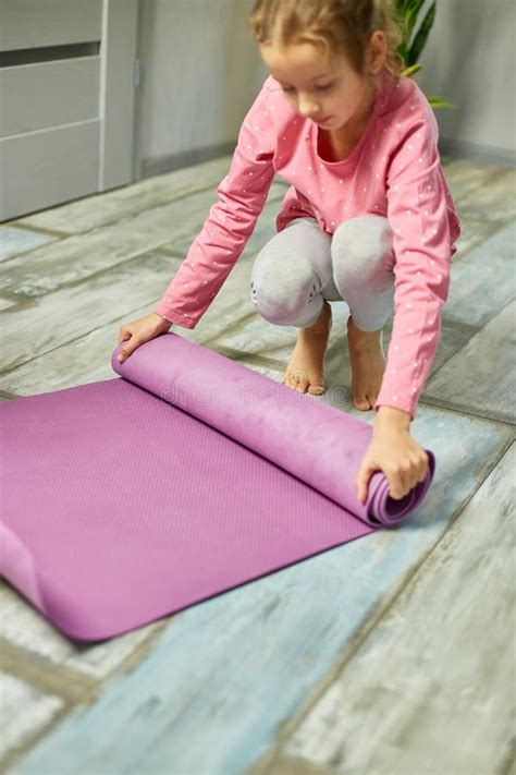 Child Little Girl Rolling Up Yoga Pilates Mat On Floor After