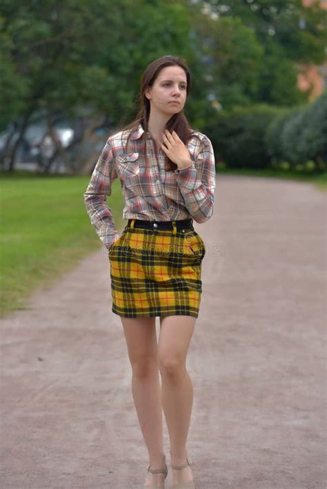 Slender Brunette Girl In A Plaid Skirt In The Summer In The Park Stock