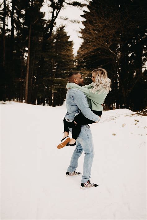 A Man Carrying A Woman On His Back In The Snow