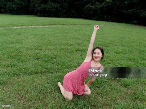 Portrait Of Young Asian Woman Kneel On Grass Field With Barefoot In